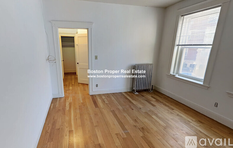 A room with wooden flooring and a window with blinds.