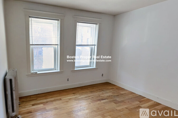 A room with wooden floors and two windows.