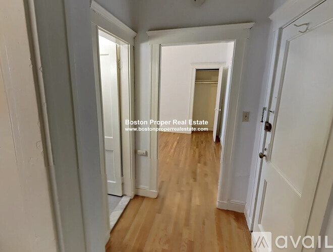 A hallway with wooden floors and white walls.