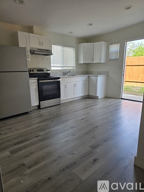 A kitchen with white appliances and cabinets with a wooden floor.