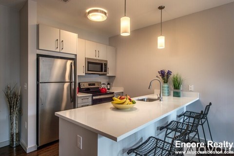 A kitchen with a refrigerator, microwave, and sink.