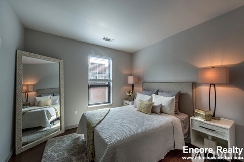 A bedroom with a large bed and a mirror on the wall.