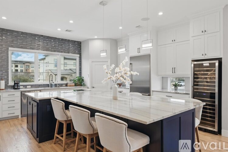 A kitchen with a large island and white chairs.