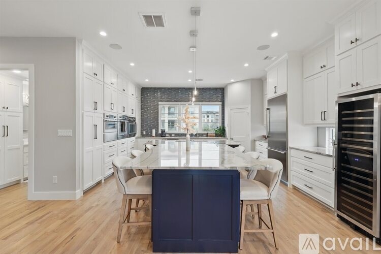 A modern kitchen with a dining table and chairs in the center.