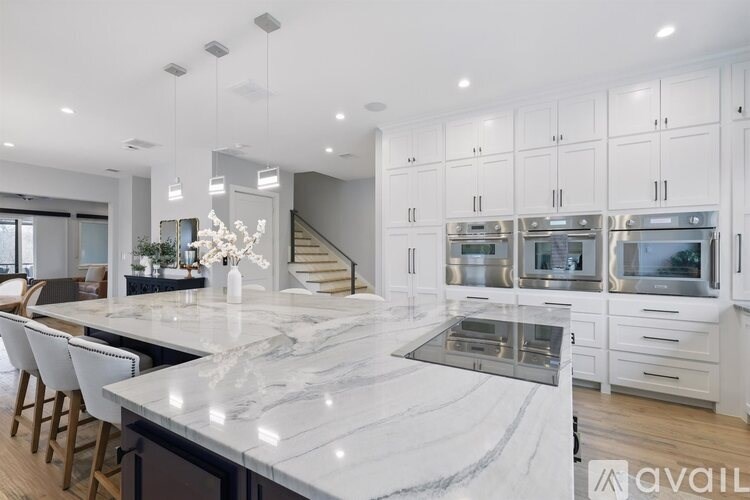 A modern kitchen with a marble countertop and stainless steel appliances.