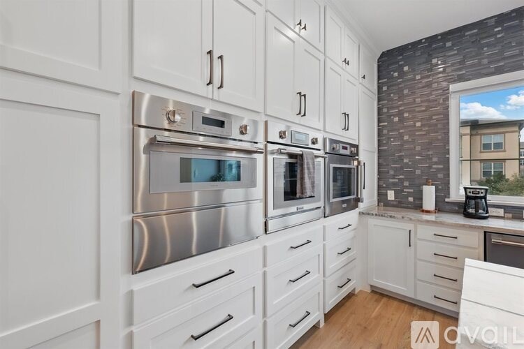 A modern kitchen with stainless steel appliances and white cabinets.