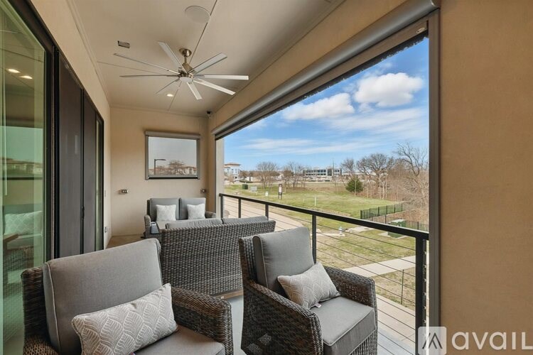 A balcony with two chairs and a table with a view of a field.