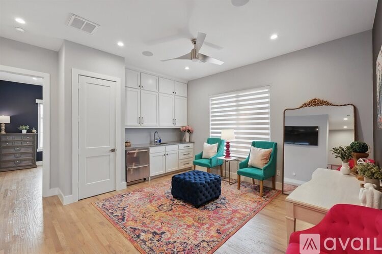 A living room with a red couch, a blue ottoman, and a rug with a wooden floor.
