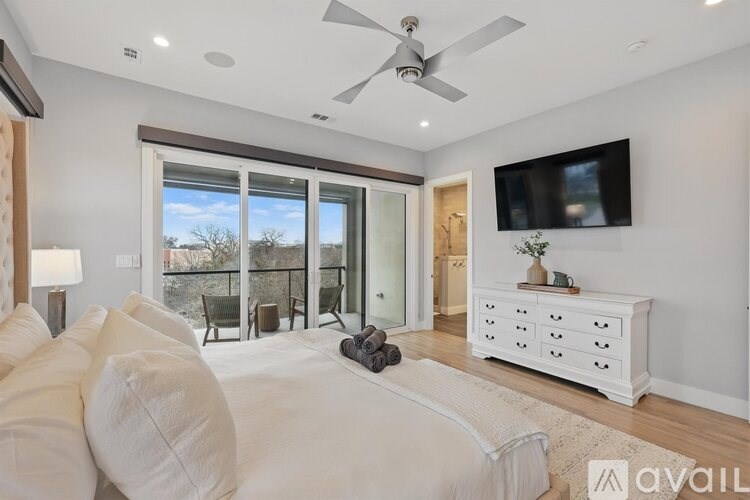 A modern living room with a large white couch and a flat screen TV mounted on the wall.