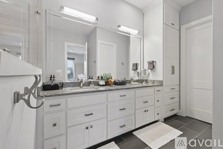 A bathroom with a white vanity and a large mirror.