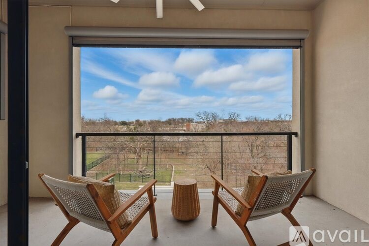 Two chairs are placed in front of a large window with a view of a field.