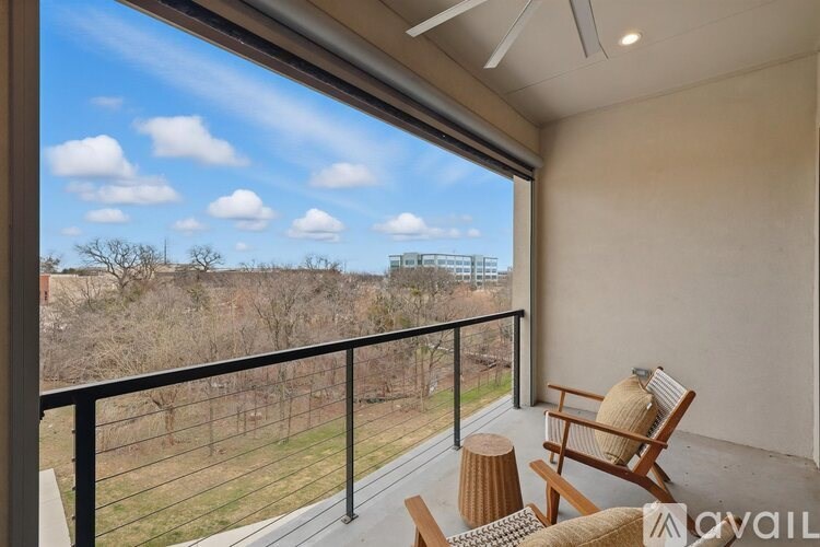 A balcony with a chair and table overlooking a field.