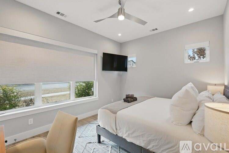 A bedroom with a large bed, a chair, and a flat-screen TV mounted on the wall.