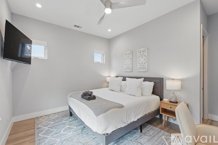 A bedroom with a large bed and a television mounted on the wall.