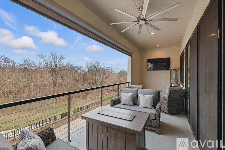 A balcony with a table and chairs overlooking a field.
