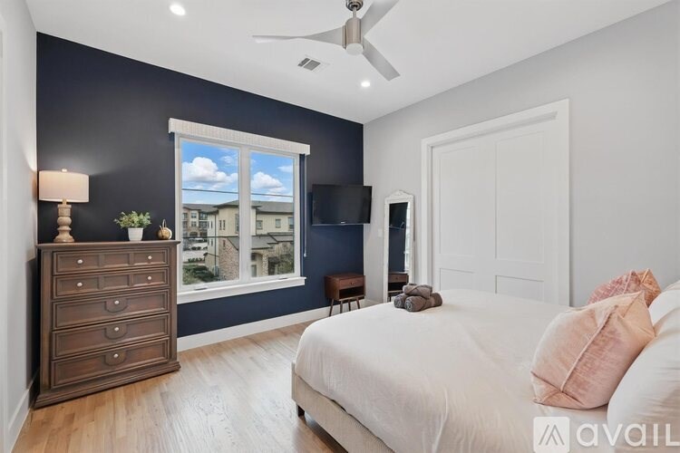 A bedroom with a bed, dresser, and window.