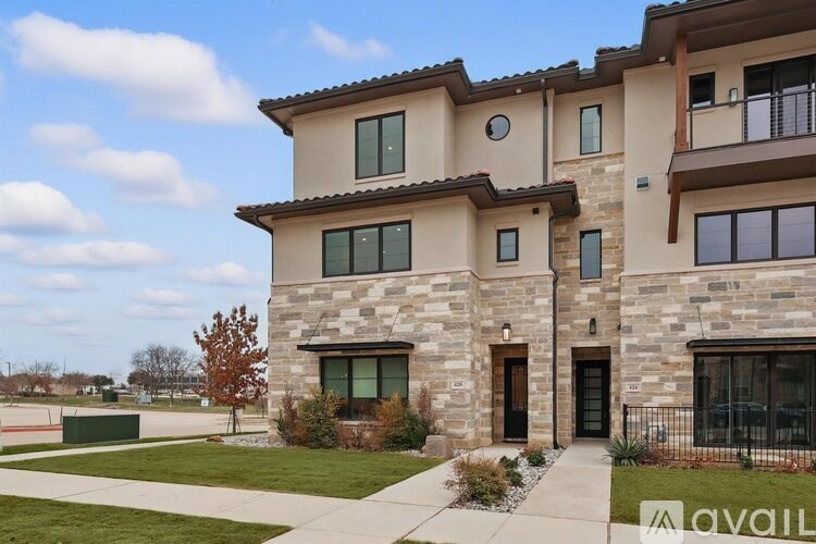 A large two-story house with a stone exterior and a balcony on the upper floor.