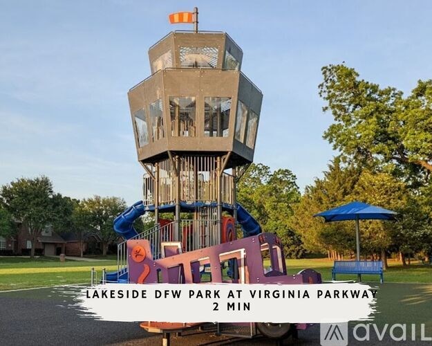 A playground with a tall tower structure and a slide in the foreground.