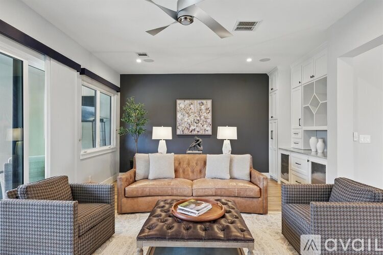 A living room with a brown couch, a coffee table, and a ceiling fan.