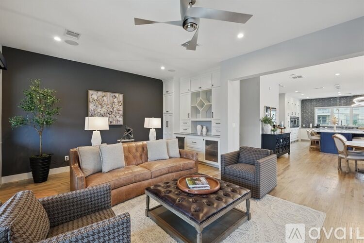 A living room with a brown couch, a coffee table, and a ceiling fan.