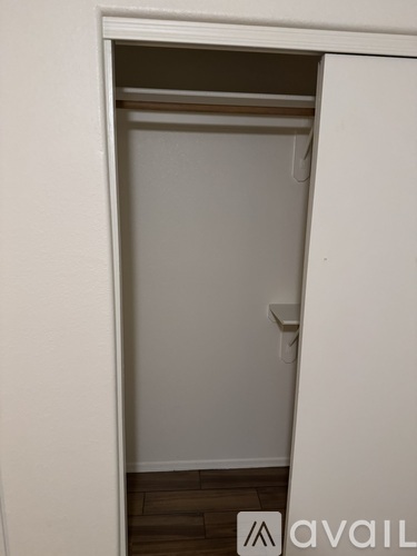 A white closet with a shelf and a white door.