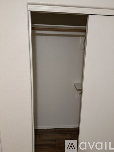 A white closet with a shelf and a white door.