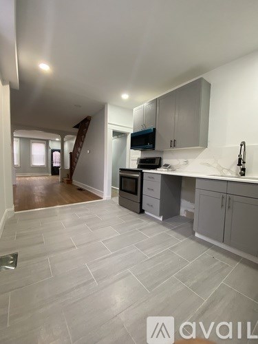 A kitchen with a white tile floor and grey cabinets.
