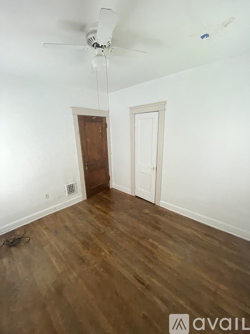 A room with a ceiling fan and wooden flooring.