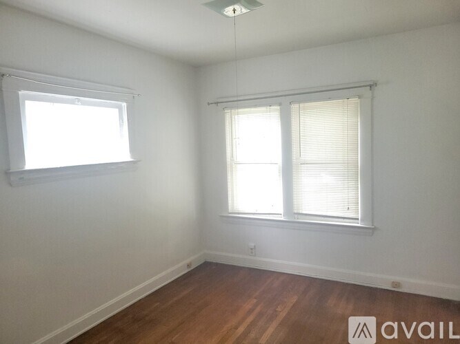 A room with wooden floors and two windows.