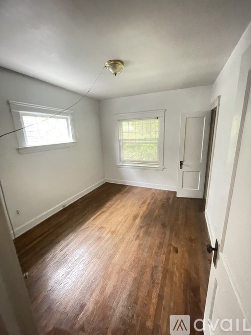 A room with wooden floors and two windows.