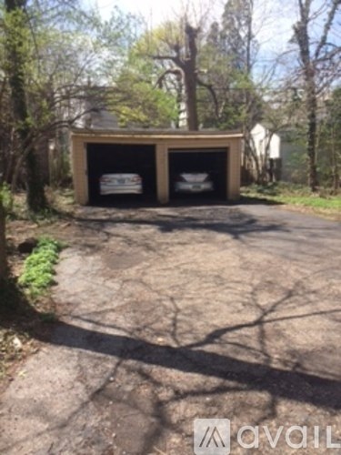A small wooden structure with two black doors is situated in a wooded area.