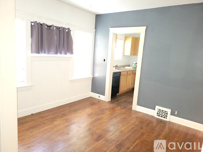 A room with wooden floors and a window with curtains.