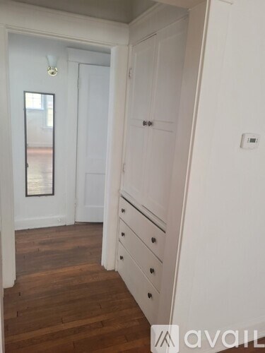 A white door with a black handle is in a room with wooden floors.