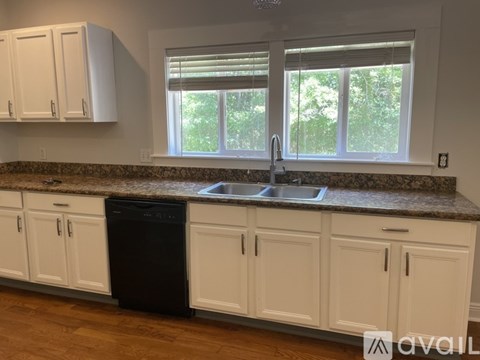 A kitchen with white cabinets and a granite countertop.
