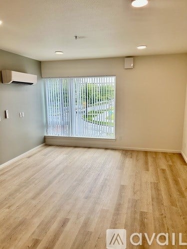 A room with wooden flooring and a window with blinds.