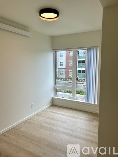 A room with a large window and wooden flooring.
