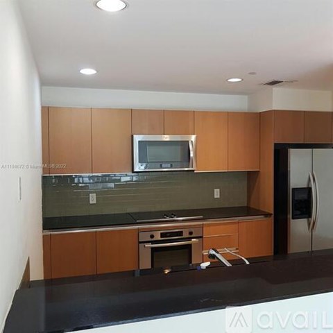A kitchen with wooden cabinets and a black countertop.