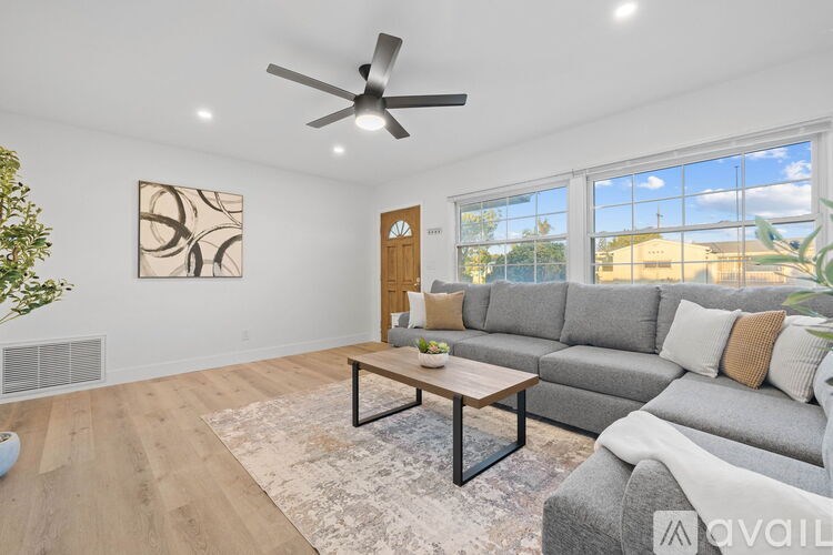 A living room with a grey couch, a coffee table, and a ceiling fan.