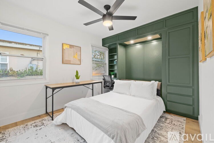 A bedroom with a bed, a table, and a ceiling fan.