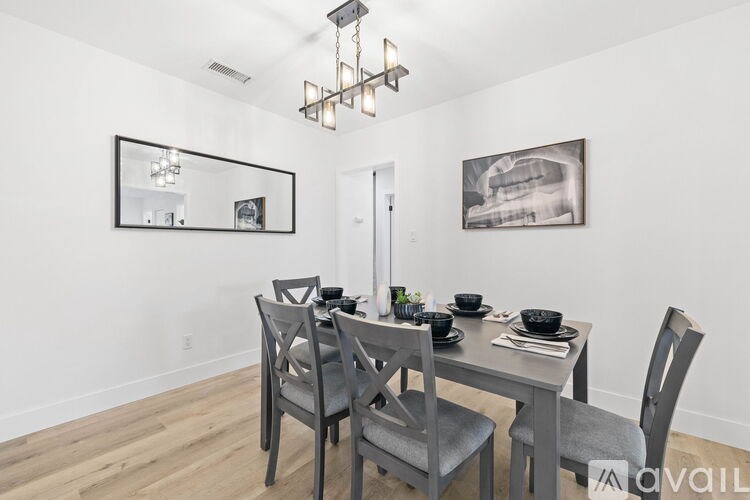 A dining room with a table set for two and a chandelier hanging from the ceiling.