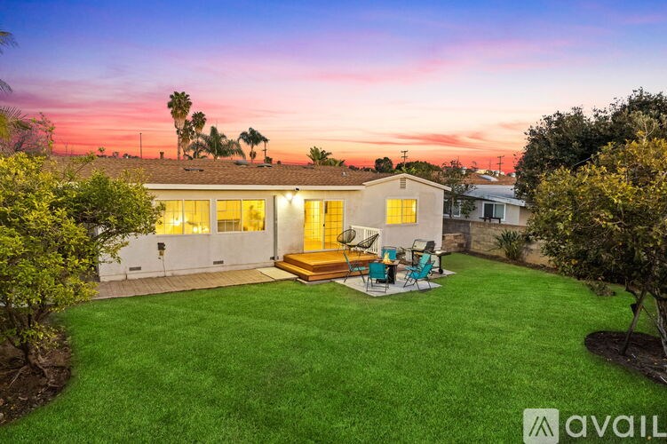 A house with a lawn and a patio with chairs and a table.