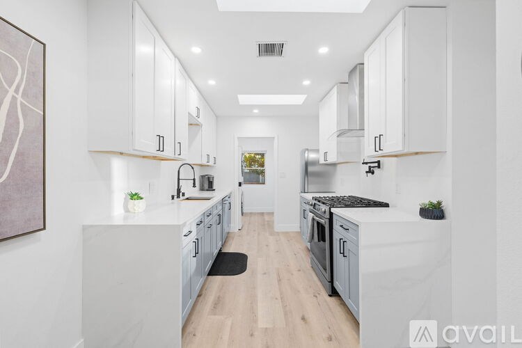 A modern kitchen with white cabinets and a wooden floor.