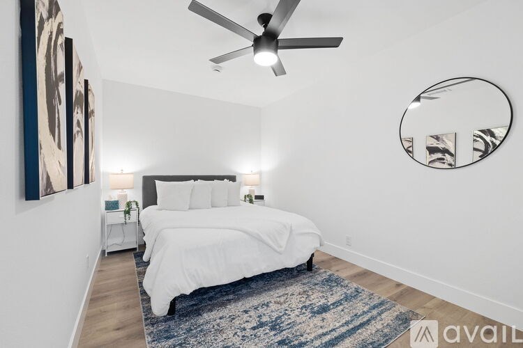 A bedroom with a bed, a ceiling fan, and a mirror on the wall.