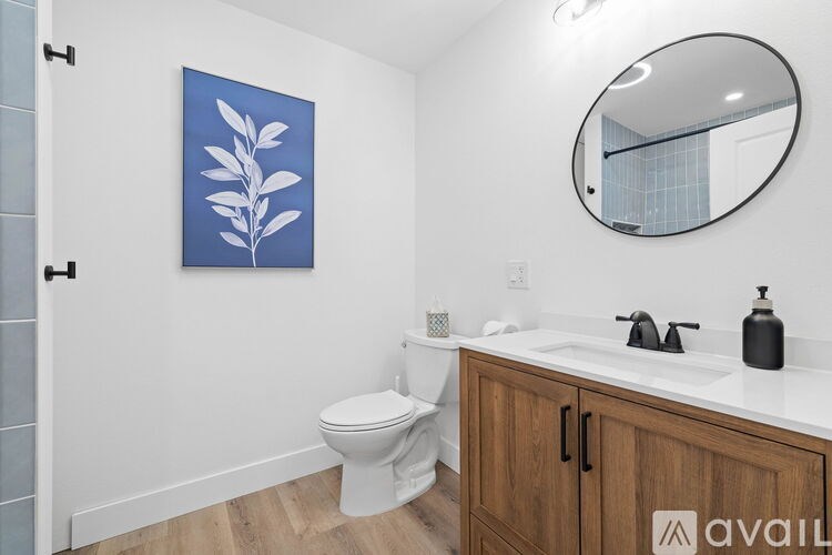 A bathroom with a toilet, sink, and a leaf-shaped painting on the wall.