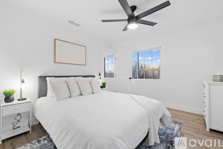 A bedroom with a large bed, a ceiling fan, and a window with a view of the outdoors.