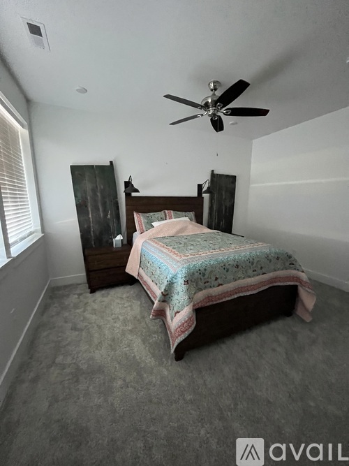 A bedroom with a bed, dresser, and ceiling fan.
