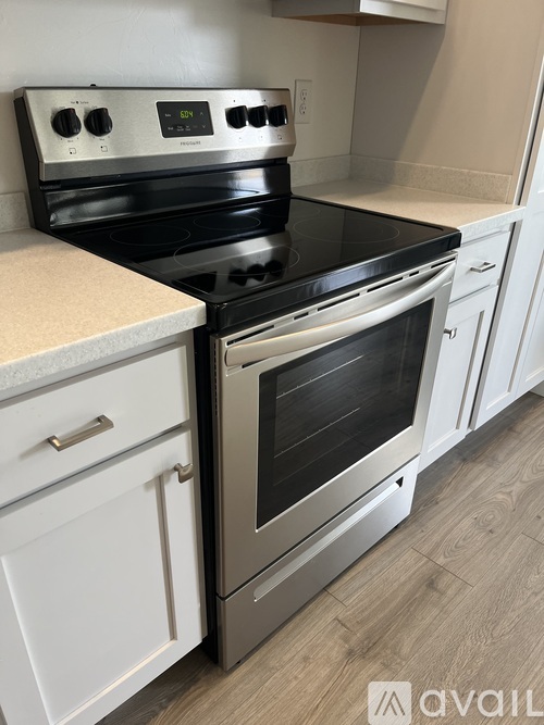 A modern kitchen with a stainless steel oven and white cabinets.