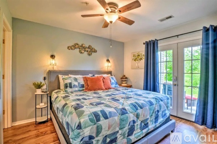 A bedroom with a bed, a ceiling fan, and a window with blue curtains.