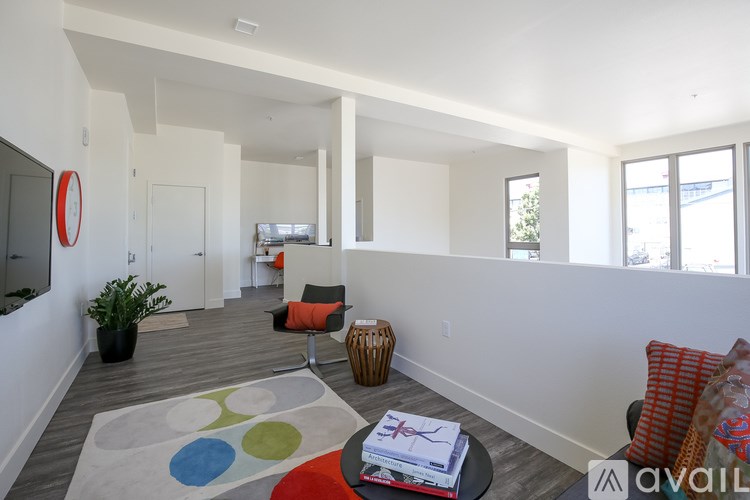 A living room with a white wall and a grey floor.
