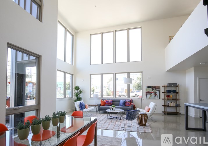 A living room with a glass table and orange chairs.
